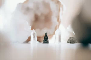 Pozitív hozzáállást szimbolizáló pici Buddha szobor rózsakvarcok között.