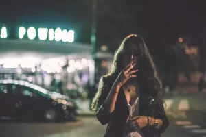 Esti jelenet a női kiégés témában: egy kiégett nő rágyújt egy cigire a bolt előtt.