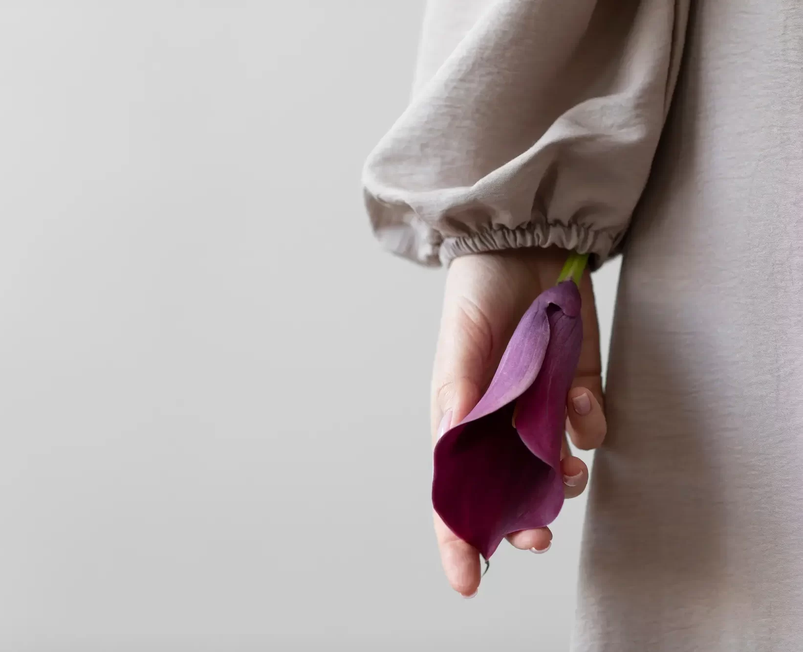 Egy nő egy virágot tart a kezében, ami most szimbolikusan a női ciklust jelképezi, különösen a premenstruációs szindróma és mindfulness kapcsolatát.